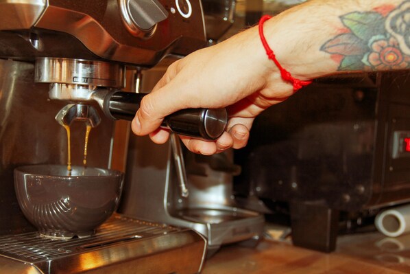 A hand operating a coffee machine, dispensing coffee into a cup. - Hotel MOLA Galata (Istanbul)