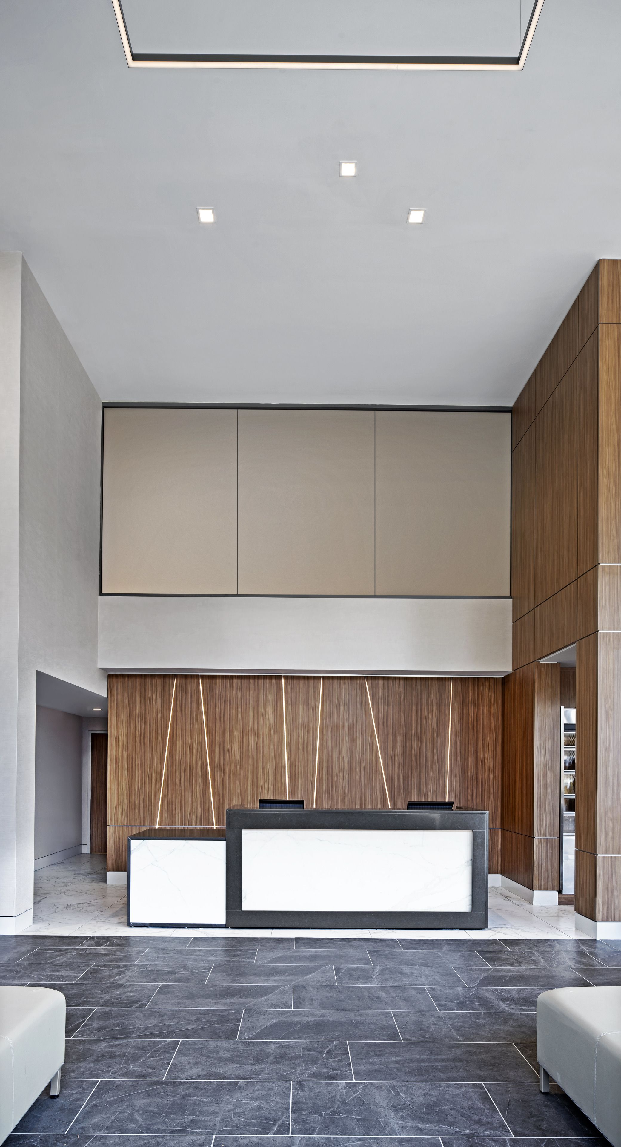A modern reception area with a reception desk, seating, and a wooden panel wall.