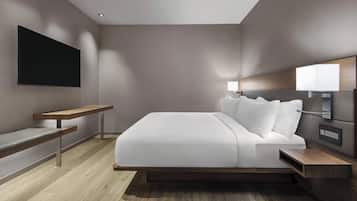 Una habitación de hotel moderna con una cama grande, una mesita de noche, un televisor montado y una lámpara de pared.