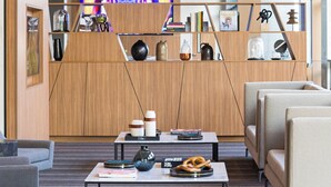 A modern interior with a central seating area, a television screen, and a wooden partition with various items displayed. - AC Hotel Louisville Downtown (Louisville)