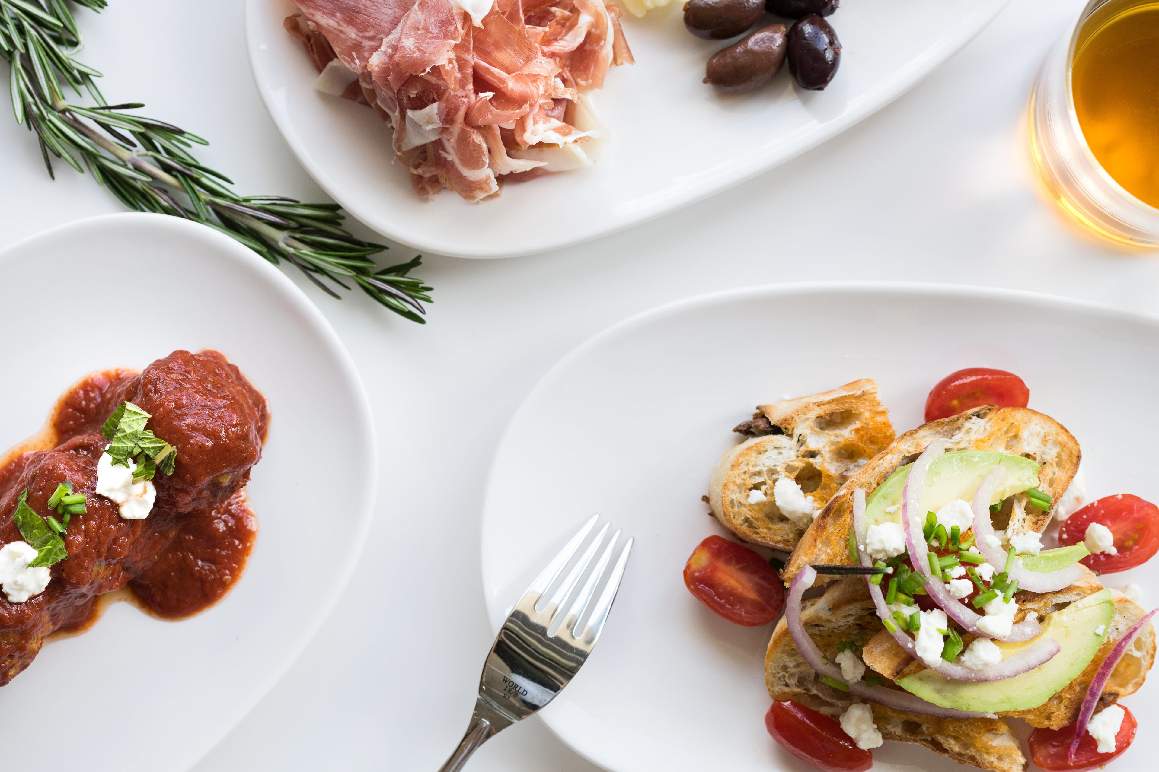 A table with various food items including meat, olives, and a drink.