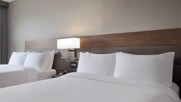 Une chambre d’hôtel avec deux lits, une table de chevet avec une lampe et une tête de lit en bois.