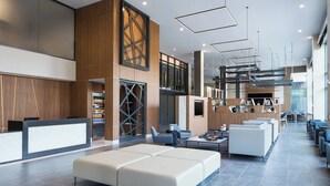 A modern hotel lobby with a reception desk, seating area, and a large window providing natural light. - AC Hotel Louisville Downtown (Louisville)