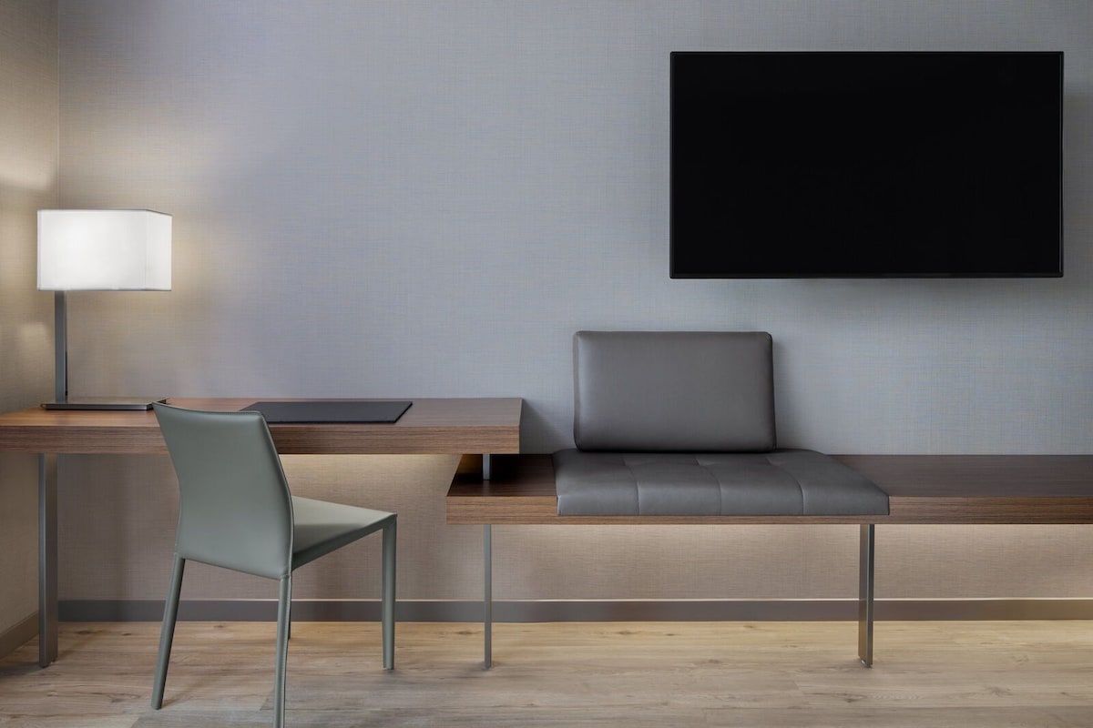 Un espacio de oficina moderno con escritorio, silla y televisor de pantalla plana montado.