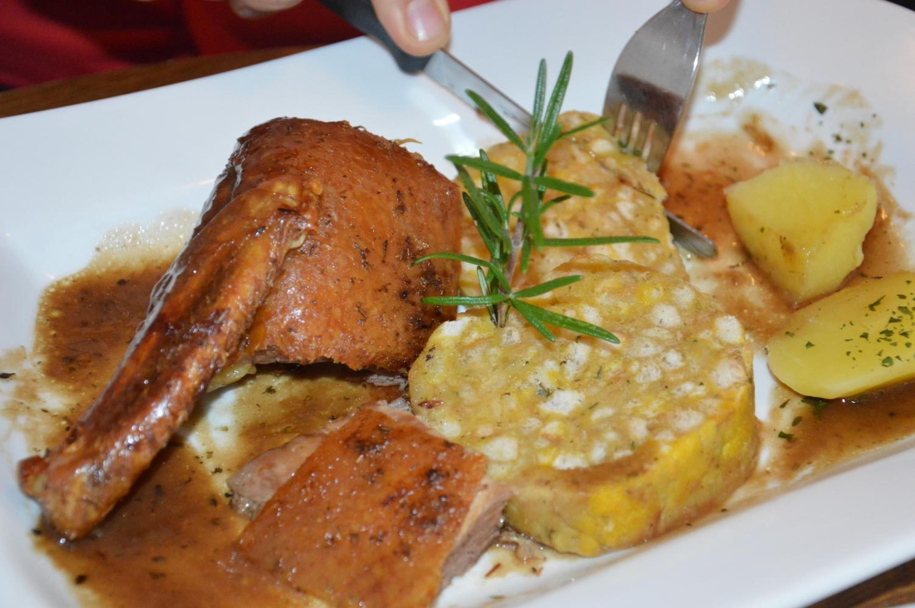 A plate with roasted chicken, potatoes, and a sprig of rosemary.