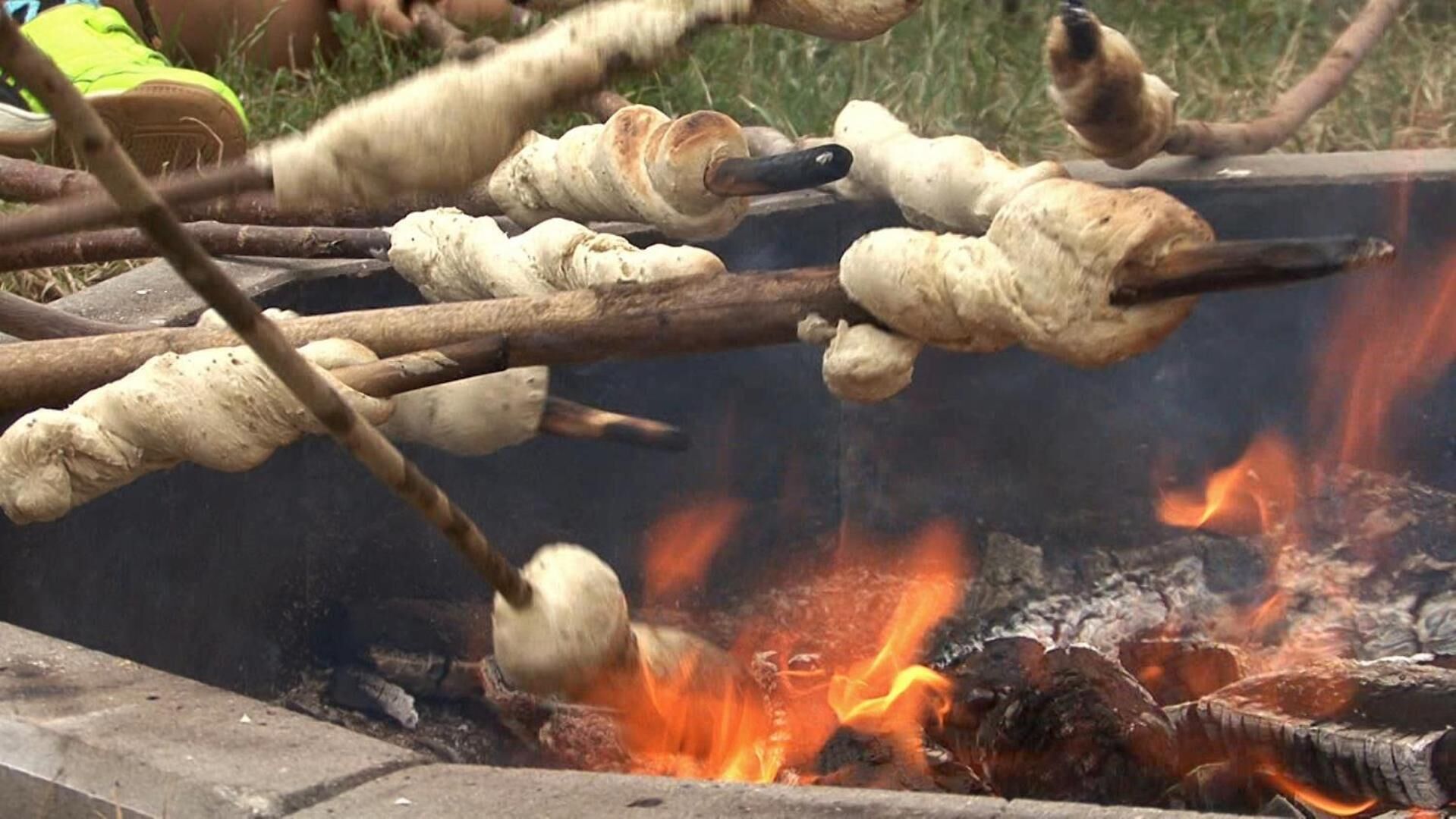 A campfire with logs and marshmallows being roasted.