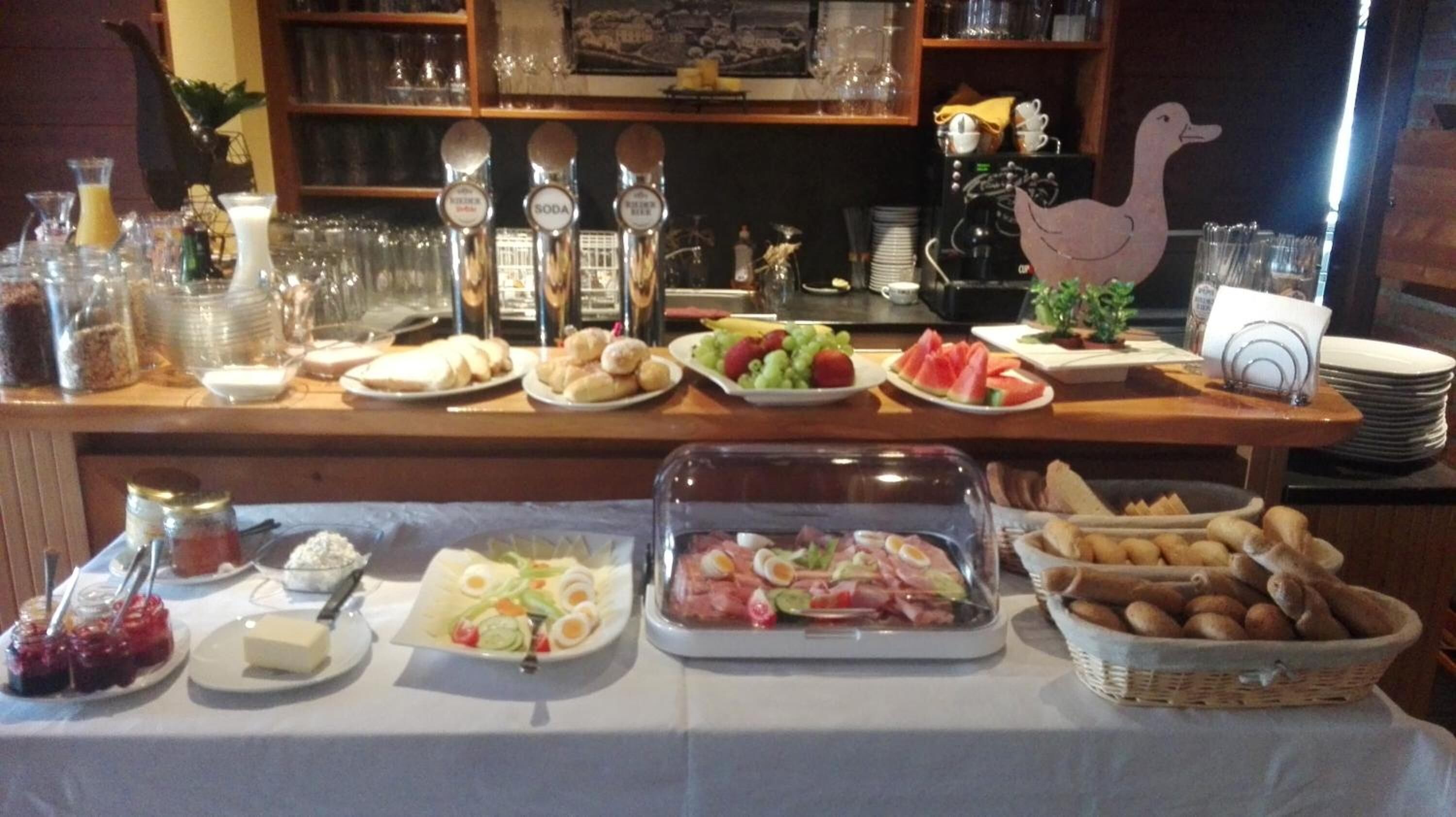 A buffet table with various food items, including fruits, bread, and a salad.