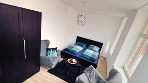 A compact bedroom with a bed, a wardrobe, a chair, and a small table. - Suite an der Furt (Erfurt)