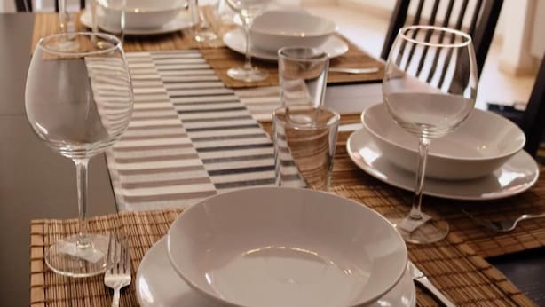 A dining table set with plates, glasses, and cutlery, with a checkered placemat. - Suite an der Furt (Erfurt)