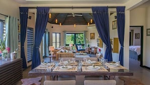 A dining area with a table set for four, a ceiling fan, and a view of the garden through the windows. - Hospitality Expert SF (Montego Bay)