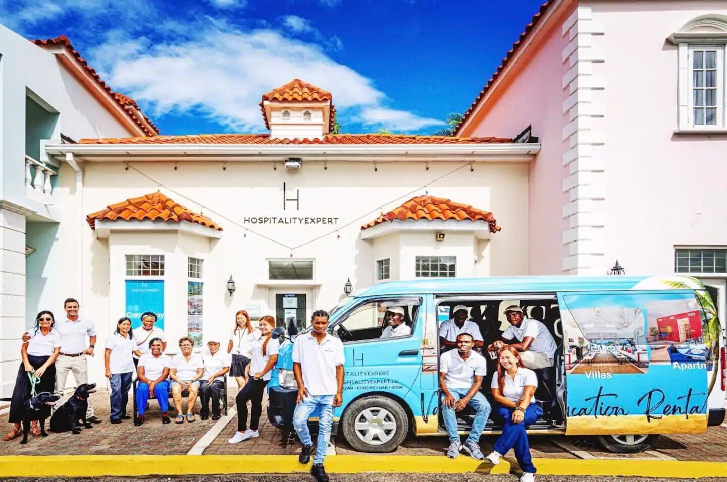 Un grupo de personas de pie frente a un edificio con un letrero que dice 'Hospitality Expert'.