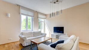 A modern living room with a white sofa, a wooden coffee table, and a flat-screen TV on a white stand. - Apartament Opera Sopot (Sopot)