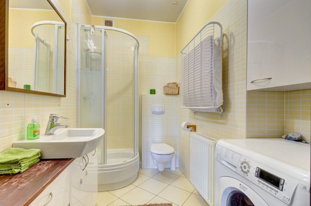 Un bagno con doccia, WC, lavandino e lavatrice.
