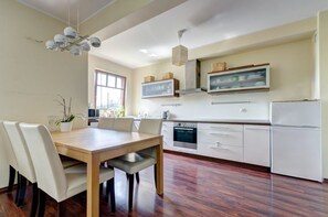 A modern kitchen with white cabinets, a wooden dining table, and a built-in oven.