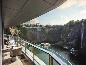 A balcony with wicker furniture overlooking a waterfall and a glass bridge. - InterContinental Shanghai Wonderland by IHG (Shanghai)