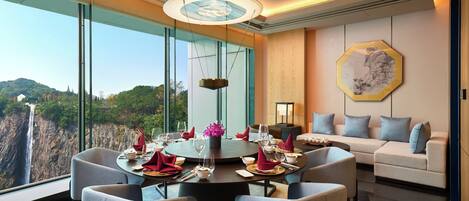 A dining area with a round table, chairs, and a view of a waterfall.