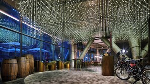 A spacious indoor area with a high ceiling adorned with hanging lights, large wooden barrels, and a motorcycle. - InterContinental Shanghai Wonderland by IHG (Shanghai)