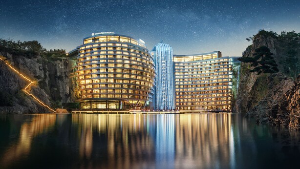 Een hotel met een rond gebouw en een hoge, smalle constructie in het midden, omgeven door water en rotsachtige kliffen.