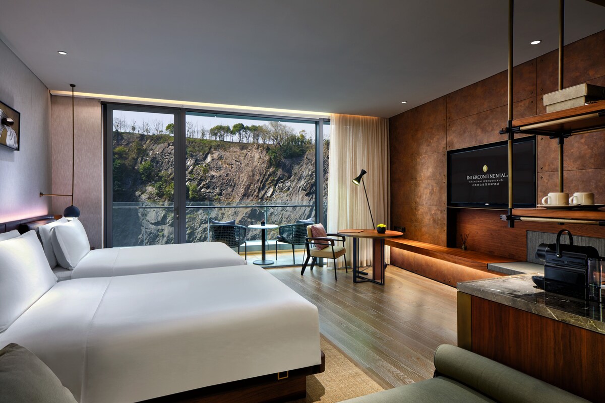 A modern hotel room with a large bed, a desk, and a TV.