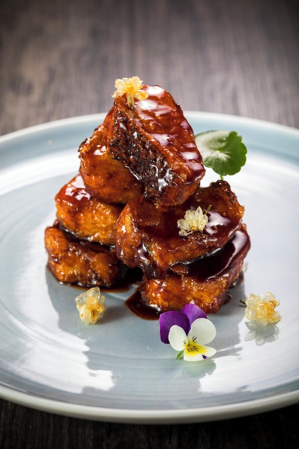 A stack of glazed meat on a plate with decorative flowers. - InterContinental Shanghai Wonderland by IHG (Shanghai)