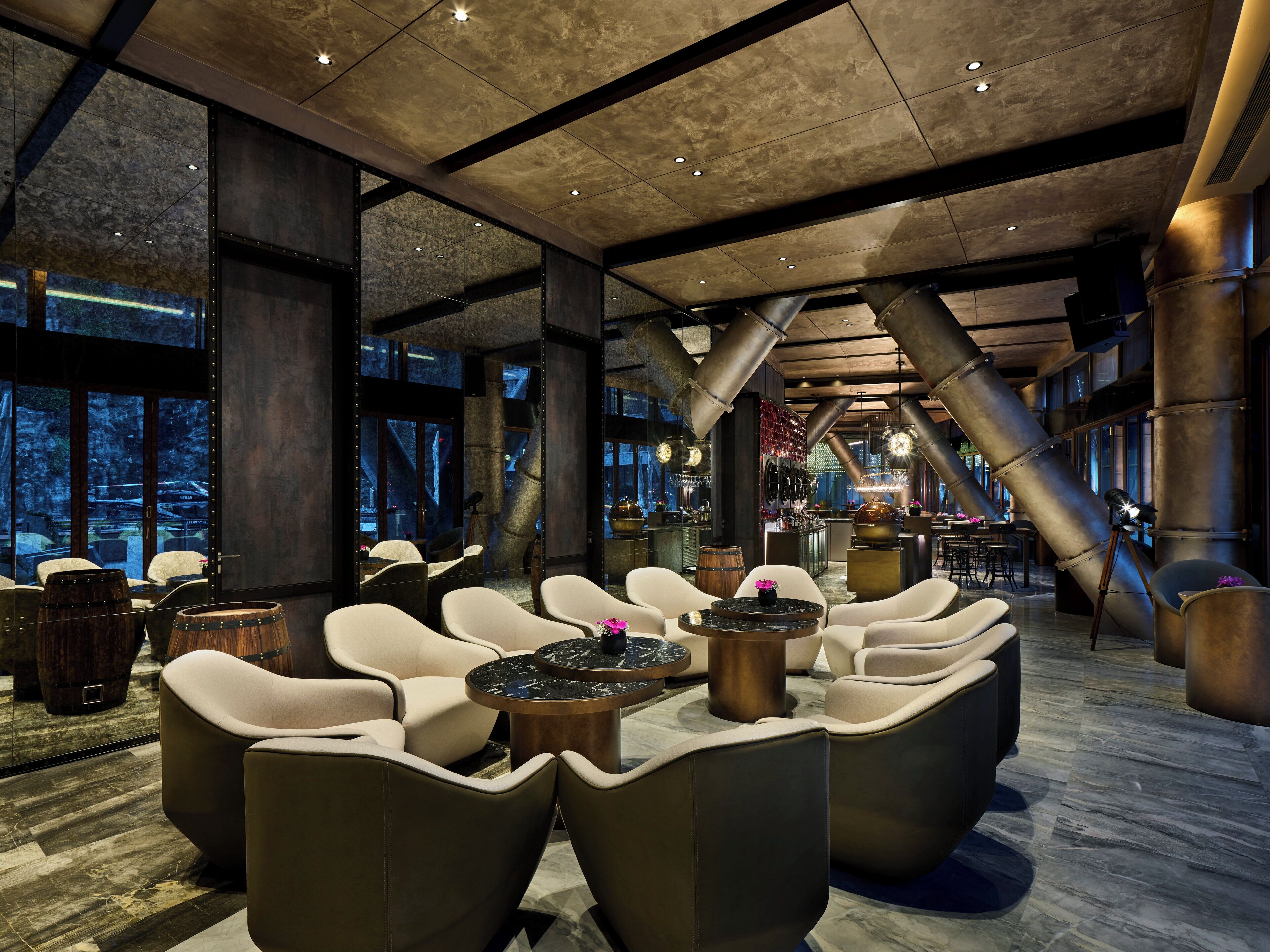 A modern lounge area with leather sofas, a bar, and large windows.