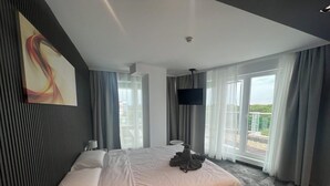 Une chambre d’hôtel moderne dotée d’un grand lit, d’une télévision à écran plat et d’un balcon avec vue.