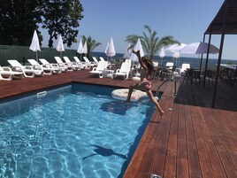 Una piscina al aire libre de temporada, sombrillas, tumbonas