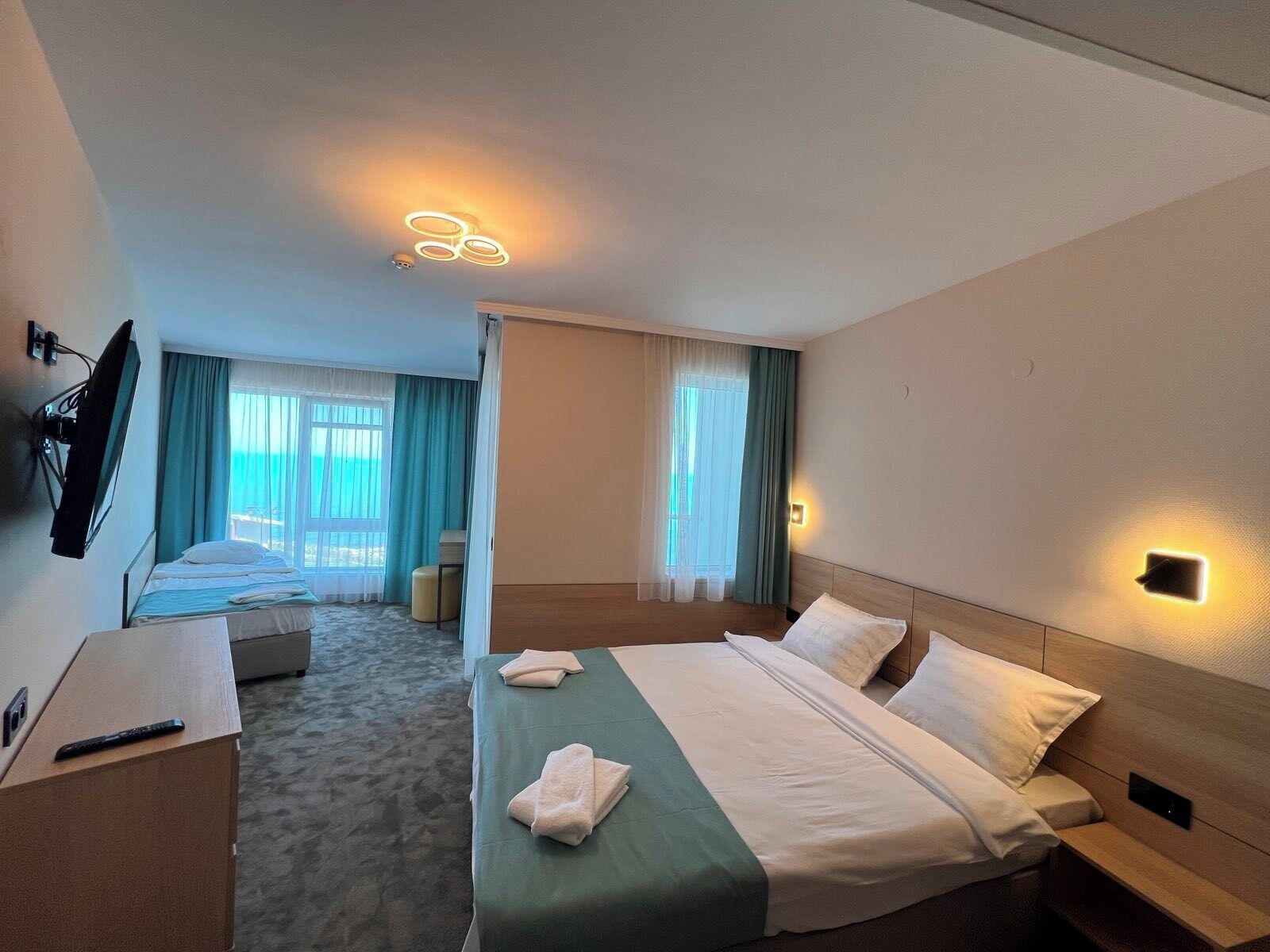 A hotel room with a bed, a desk, a chair, a television, and a window with curtains.