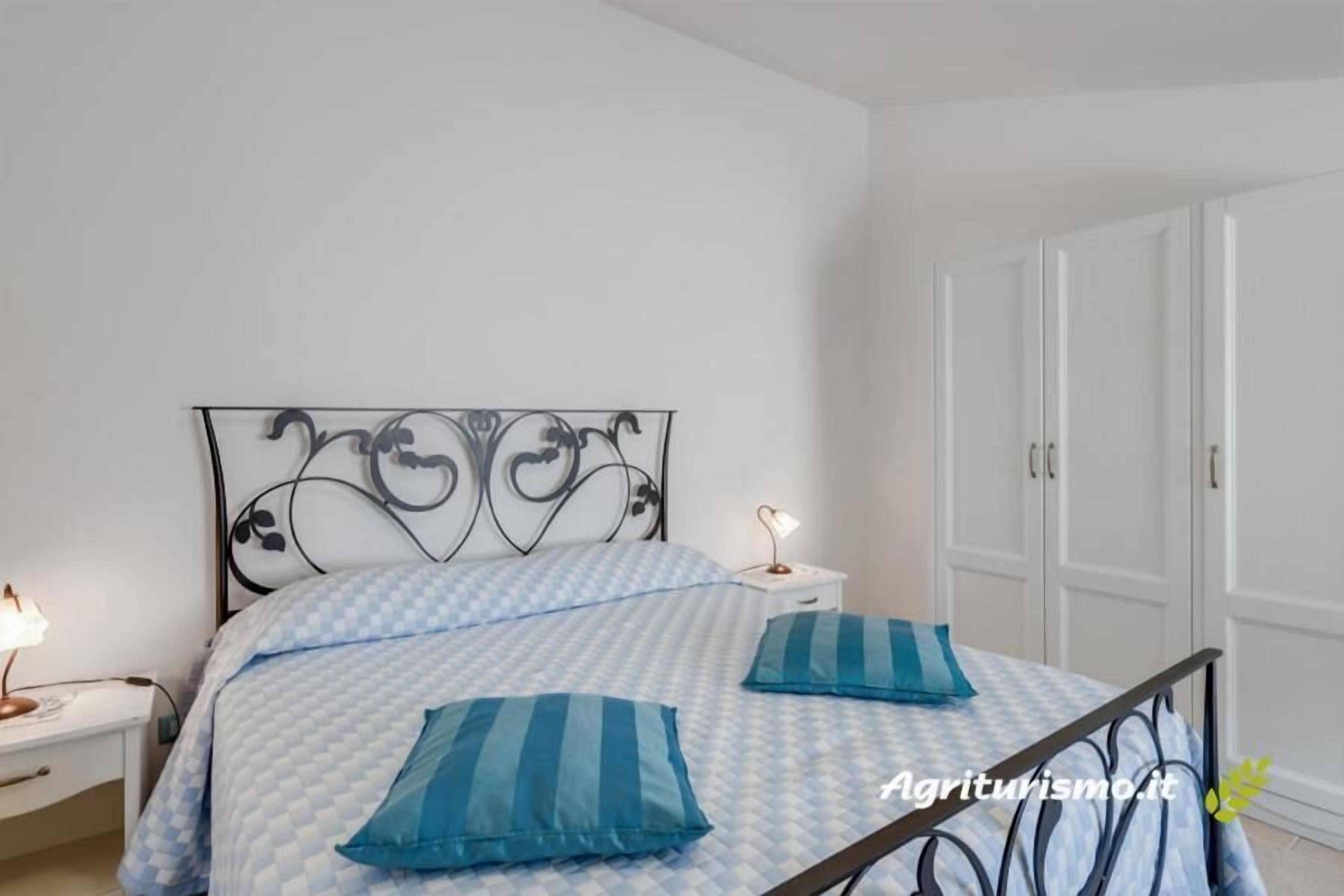 A bedroom with a bed, nightstands, and a wardrobe.