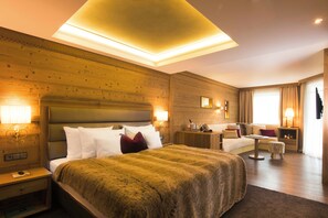 A hotel room with a large bed, a small table, a sofa, and a nightstand with a lamp. - Landromantik Hotel Oswald Gourmet & SPA (Teisnach)