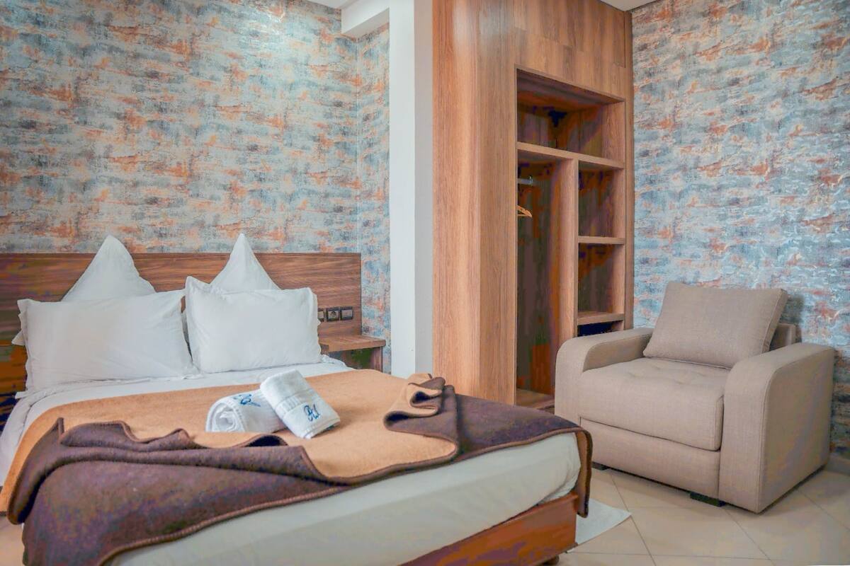 A bedroom with a bed, a sofa, and a wooden wardrobe.