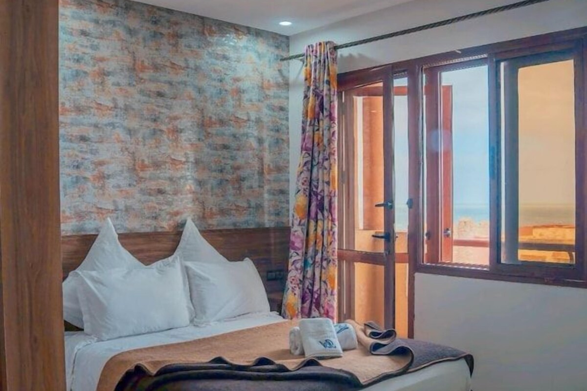 A bedroom with a bed, a window with curtains, and a view outside.
