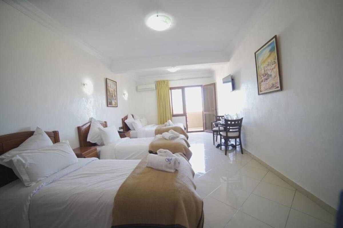 A hotel room with two beds, a desk, and a chair.