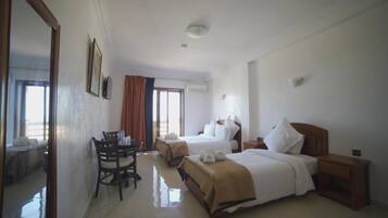 A hotel room with two beds, a dining table, and a mirror.