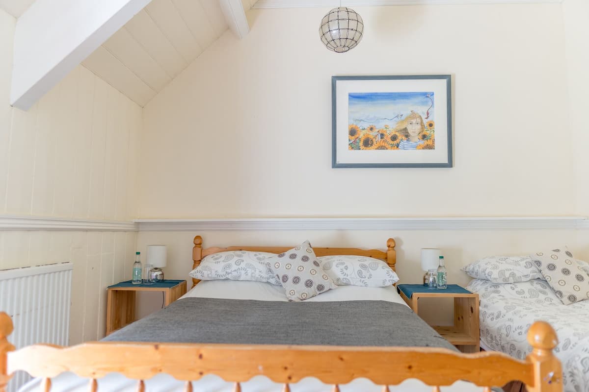 A bedroom with a wooden bed, two bedside tables, a framed painting, and a radiator.