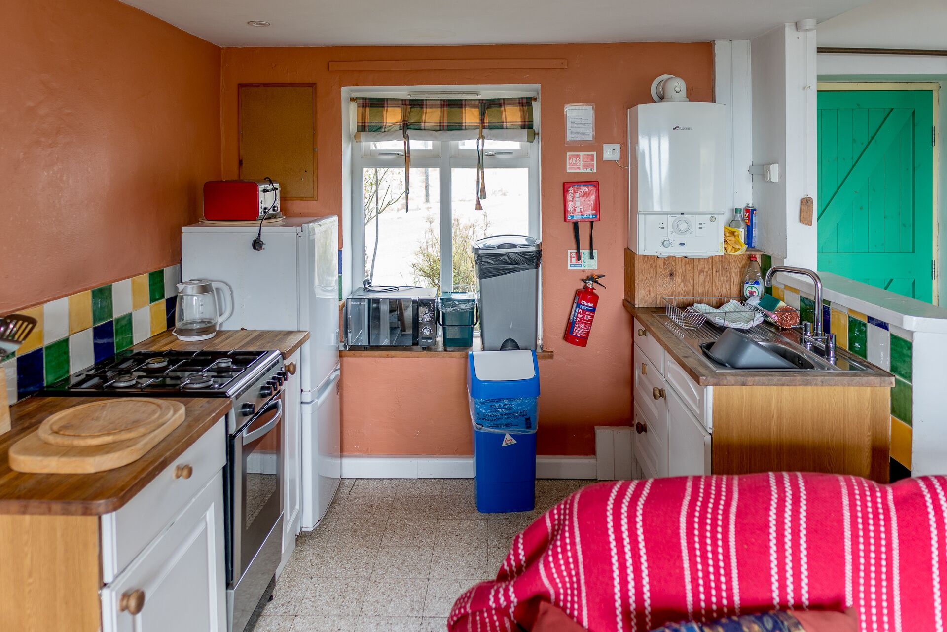 A compact kitchen with a gas stove, a refrigerator, a microwave, and a sink.