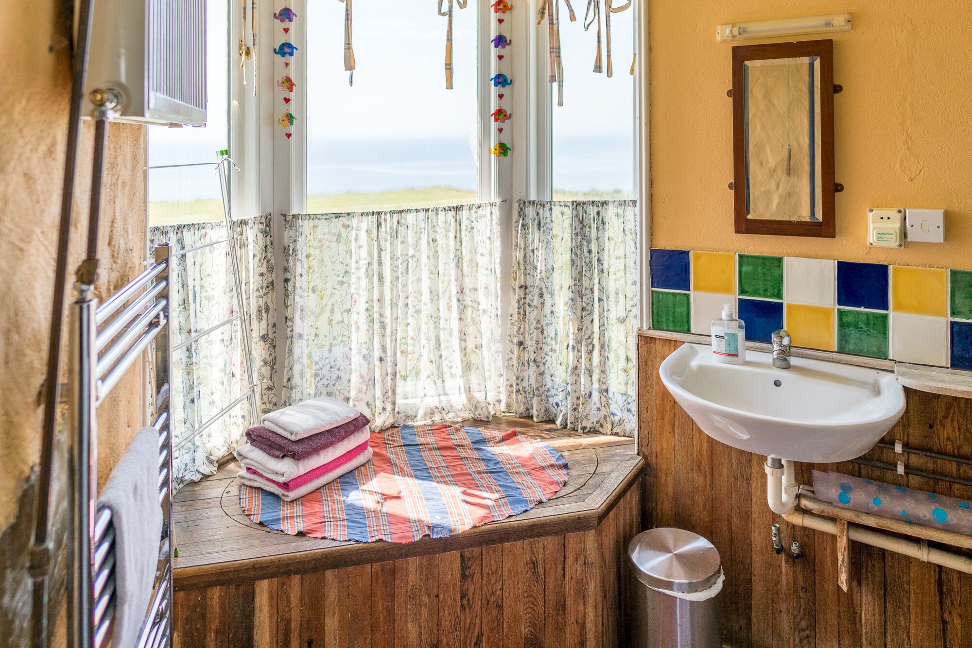 A bathroom with a wooden vanity, a sink, and a window with floral curtains.