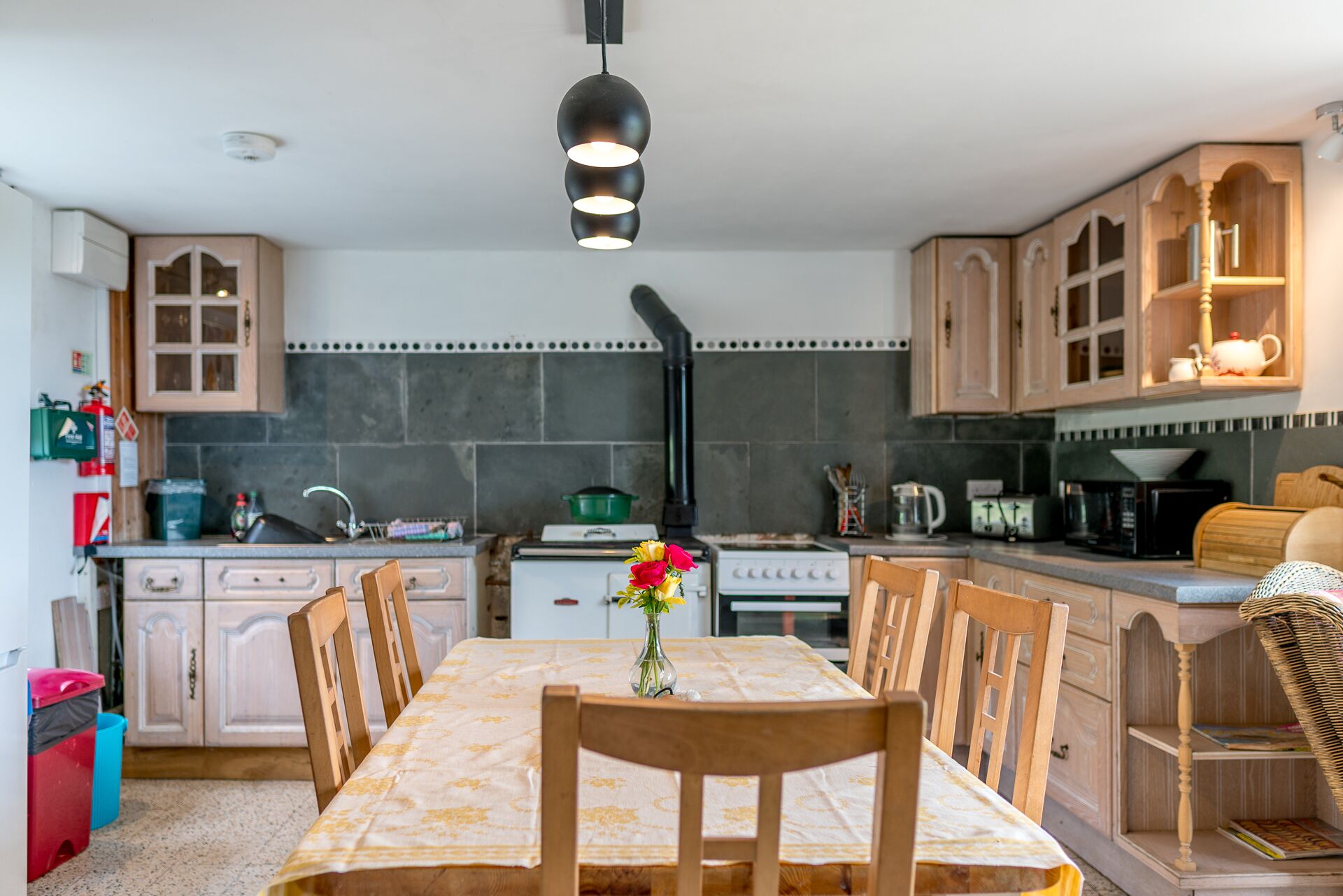 Une cuisine avec des meubles de rangement en bois, une cuisinière et une table à manger avec des chaises.
