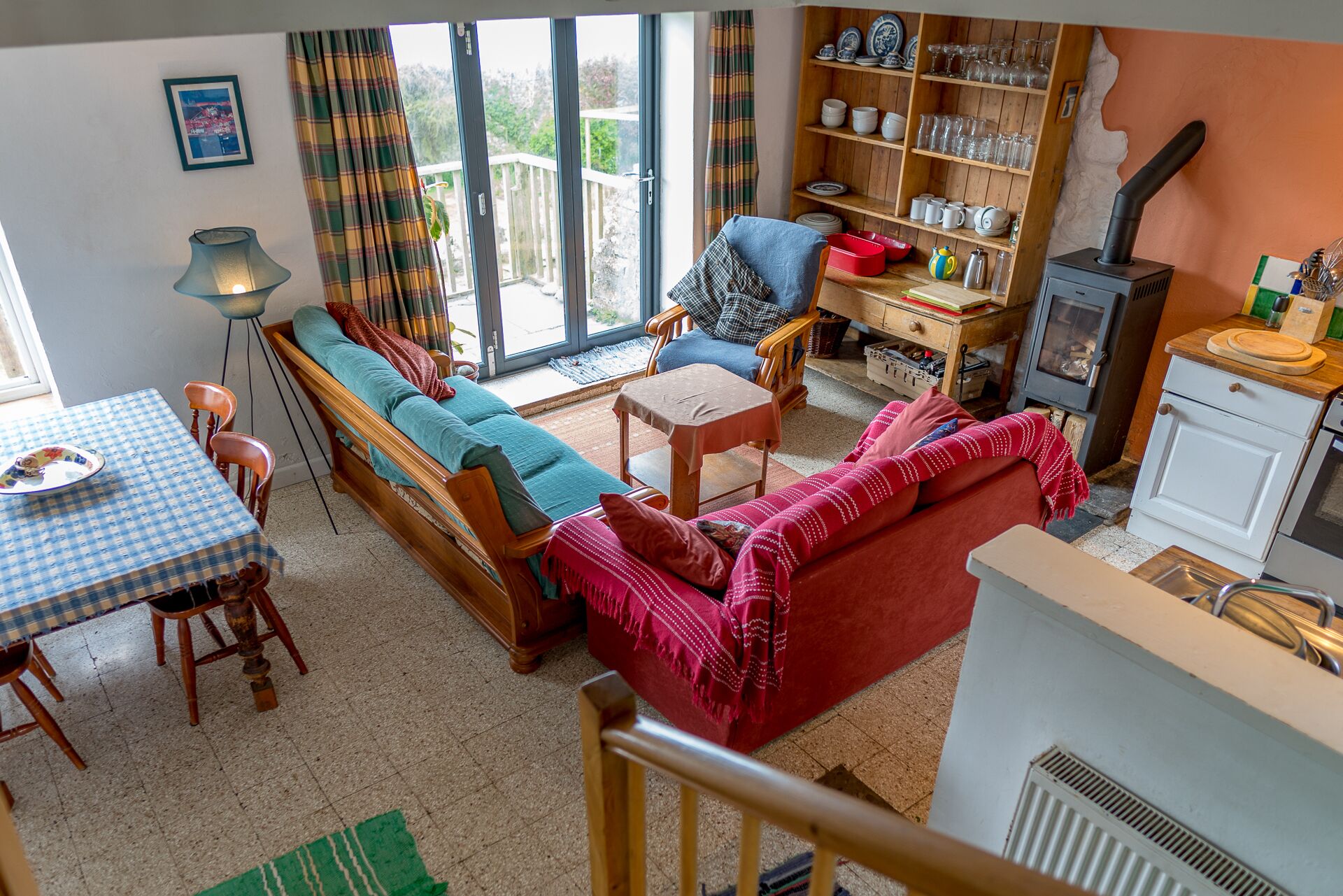 Ein gemütliches Wohnzimmer mit Sofa, Esstisch mit Stühlen, Kamin und Blick durch die Glastür.