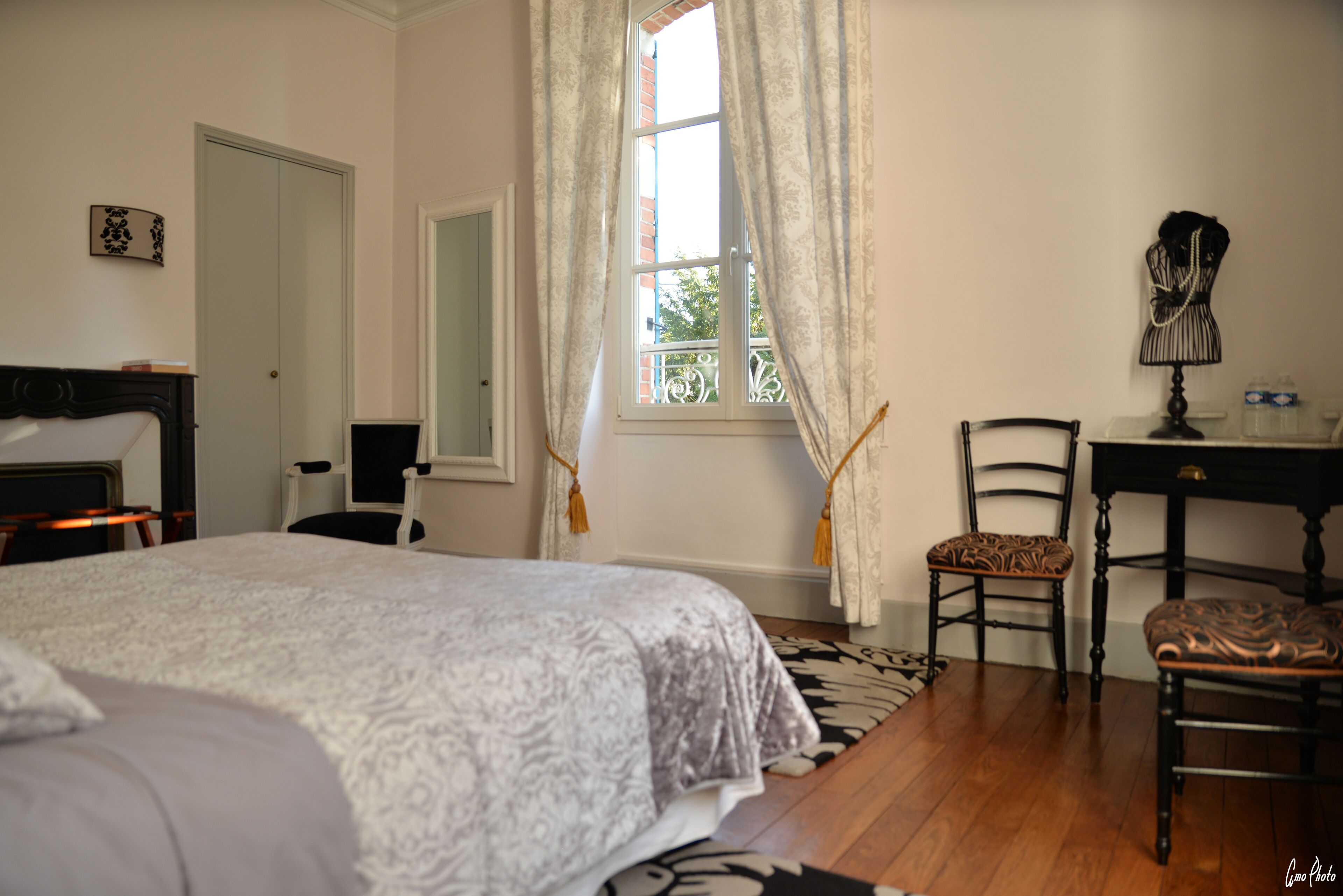 Un dormitorio con una cama grande, dos sillones, un escritorio y una ventana con cortinas.