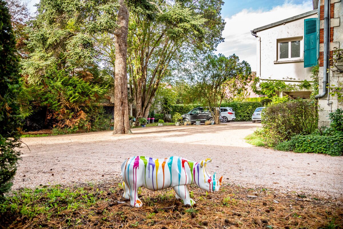 A residential street with a colorful painted rhinoceros sculpture in the foreground.