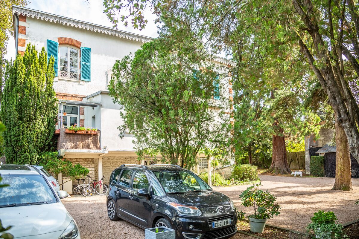 A residential property with a parked car, a bicycle, and a dog in the yard.