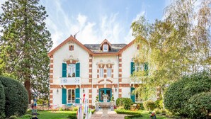A two-story building with a symmetrical facade, a central entrance with a decorative stone archway, and a small fountain in the courtyard. - L'Oustal (Bourges)