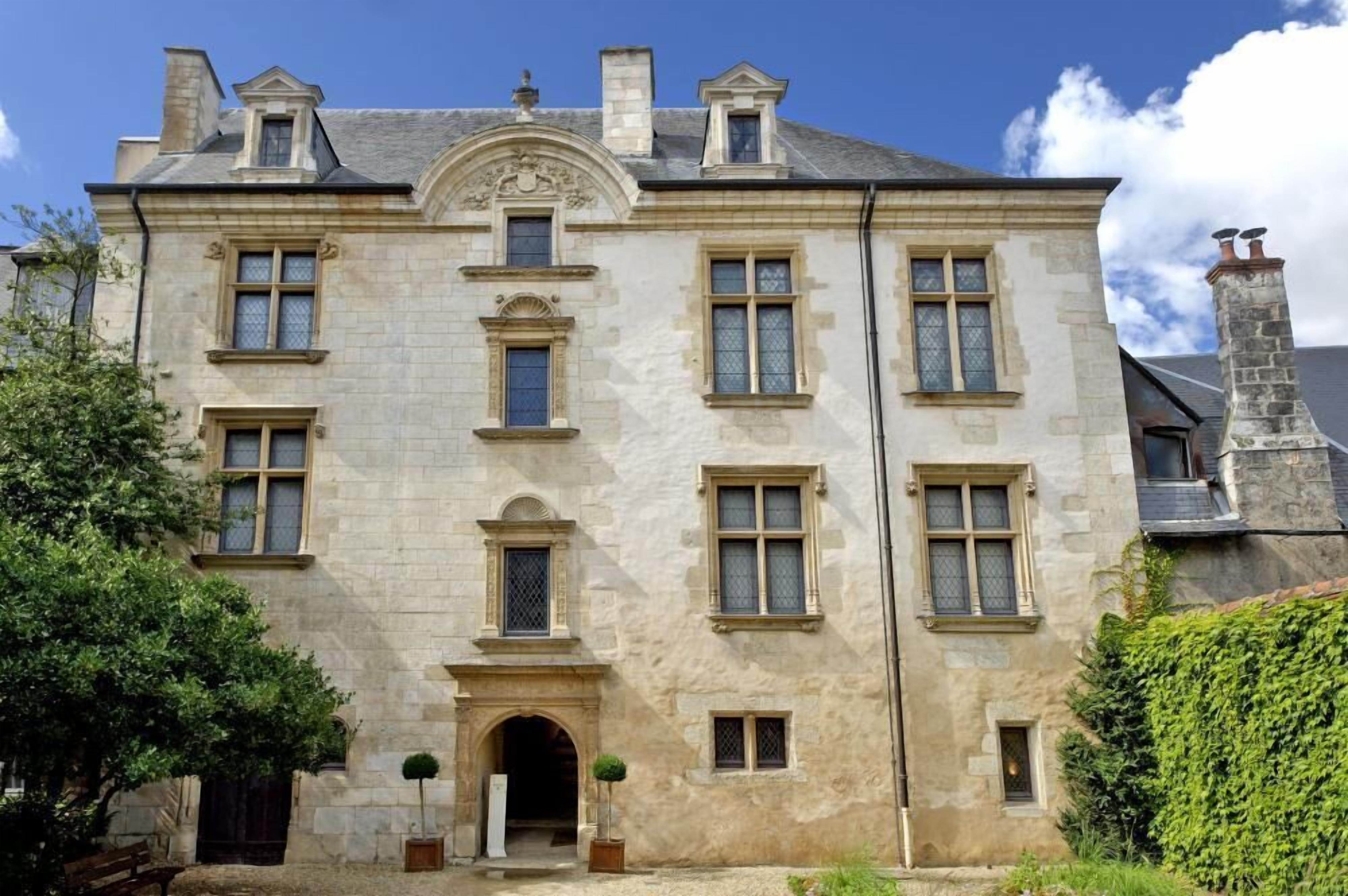 Un edificio de piedra grande con varias ventanas y una entrada central.