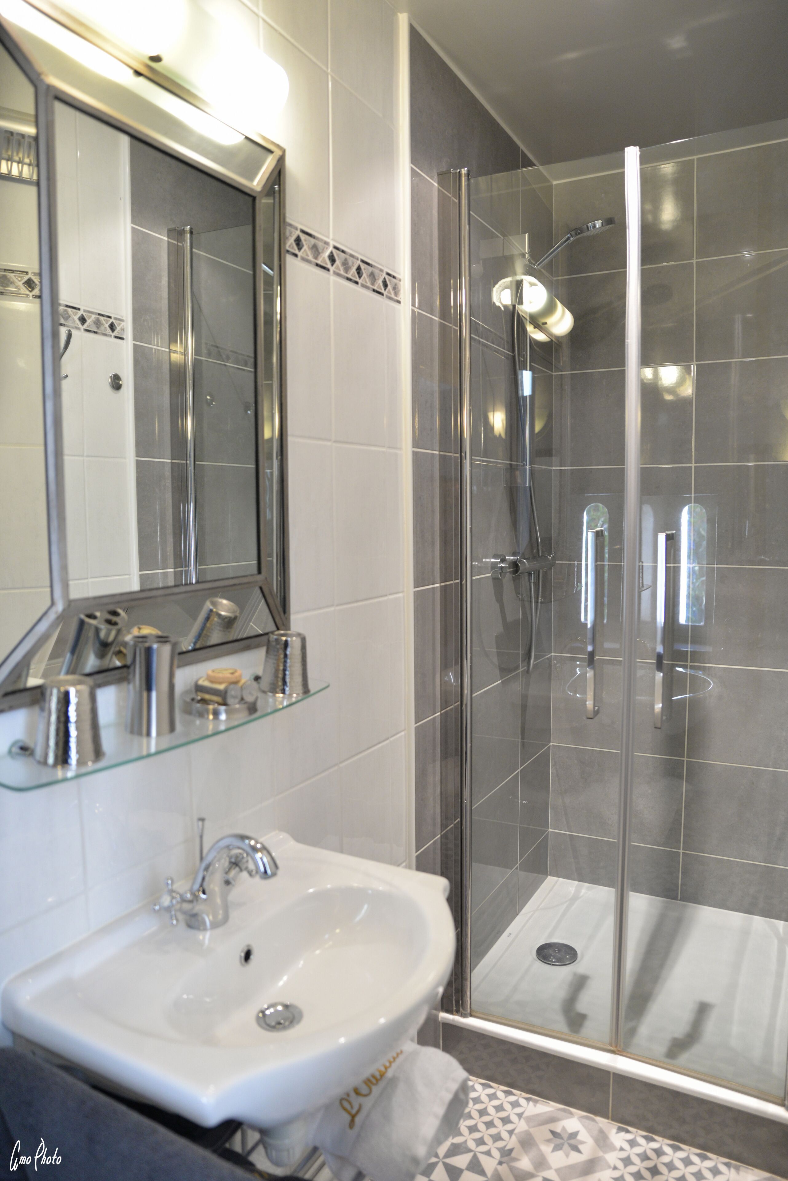 A bathroom with a glass shower enclosure, a sink, and a mirror.