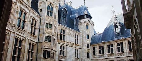 Um edifício histórico com arquitetura elaborada, grandes janelas e um pátio.