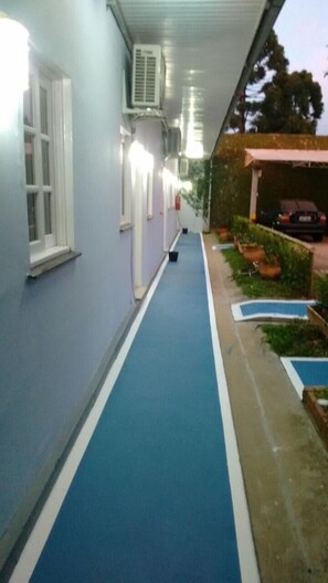 Stroll through the corridor to the pool area, surrounded by lush greenery and a convenient parking spot.