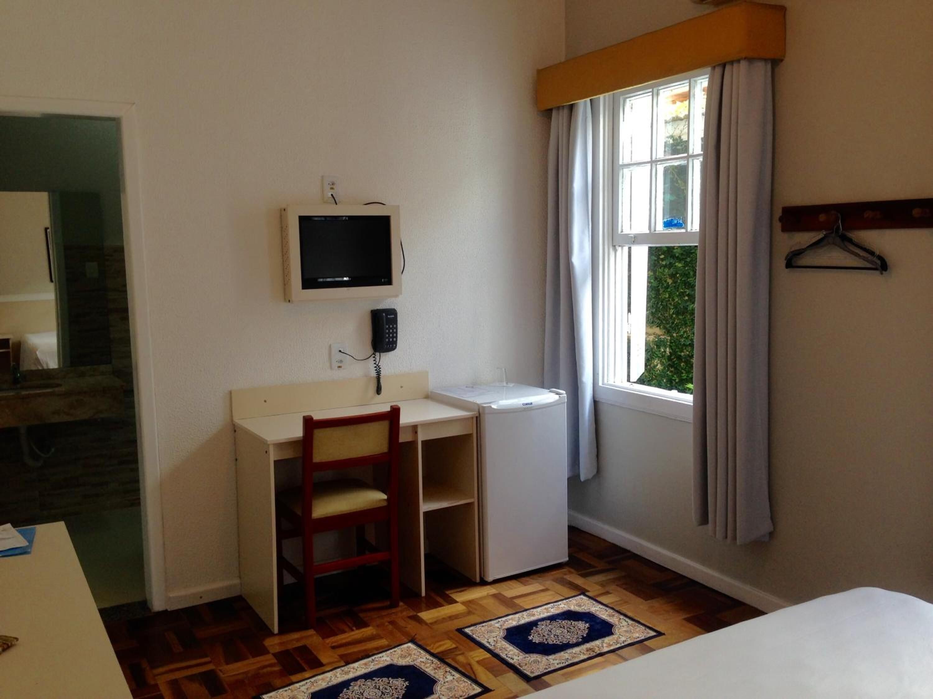 A small room with a desk, chair, and a television mounted on the wall.
