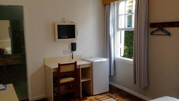 A small room with a desk, chair, and a television mounted on the wall.