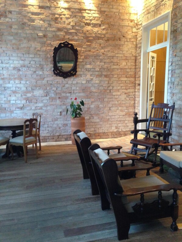 A cozy room with a brick wall, wooden furniture, and a potted plant. - Central Palace Hotel (Castro)